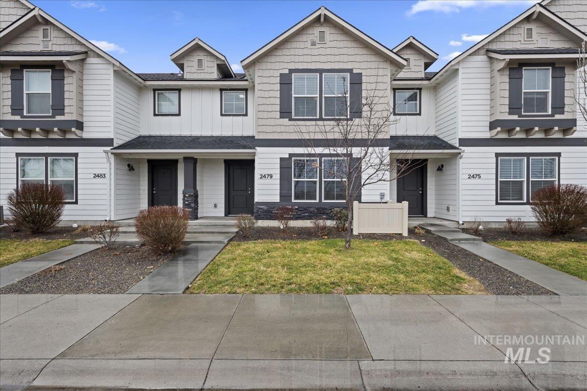 View of front of property with board and batten siding, roof with shingles, and a front lawn
