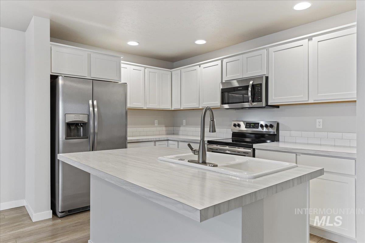 2479 East Goldstone Street Meridian, ID 83642 - Photo 11 of 29 Kitchen with light countertops, stainless steel appliances, white cabinetry, a kitchen island with sink, and recessed lighting