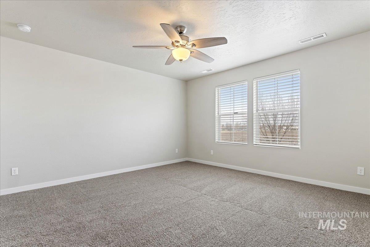 2479 East Goldstone Street Meridian, ID 83642 - Photo 14 of 29 Empty room with light carpet, a ceiling fan, and a textured ceiling