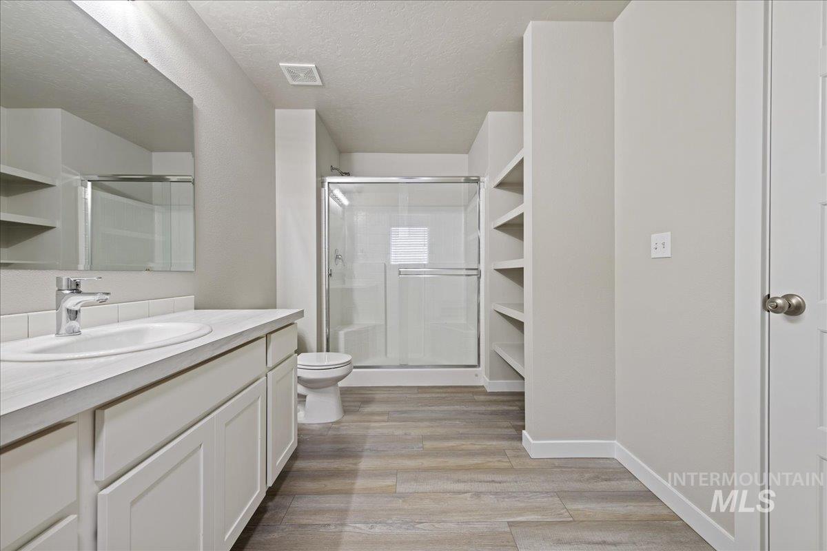 2479 East Goldstone Street Meridian, ID 83642 - Photo 20 of 29 Full bath with vanity, a shower stall, light wood-style flooring, and a textured ceiling