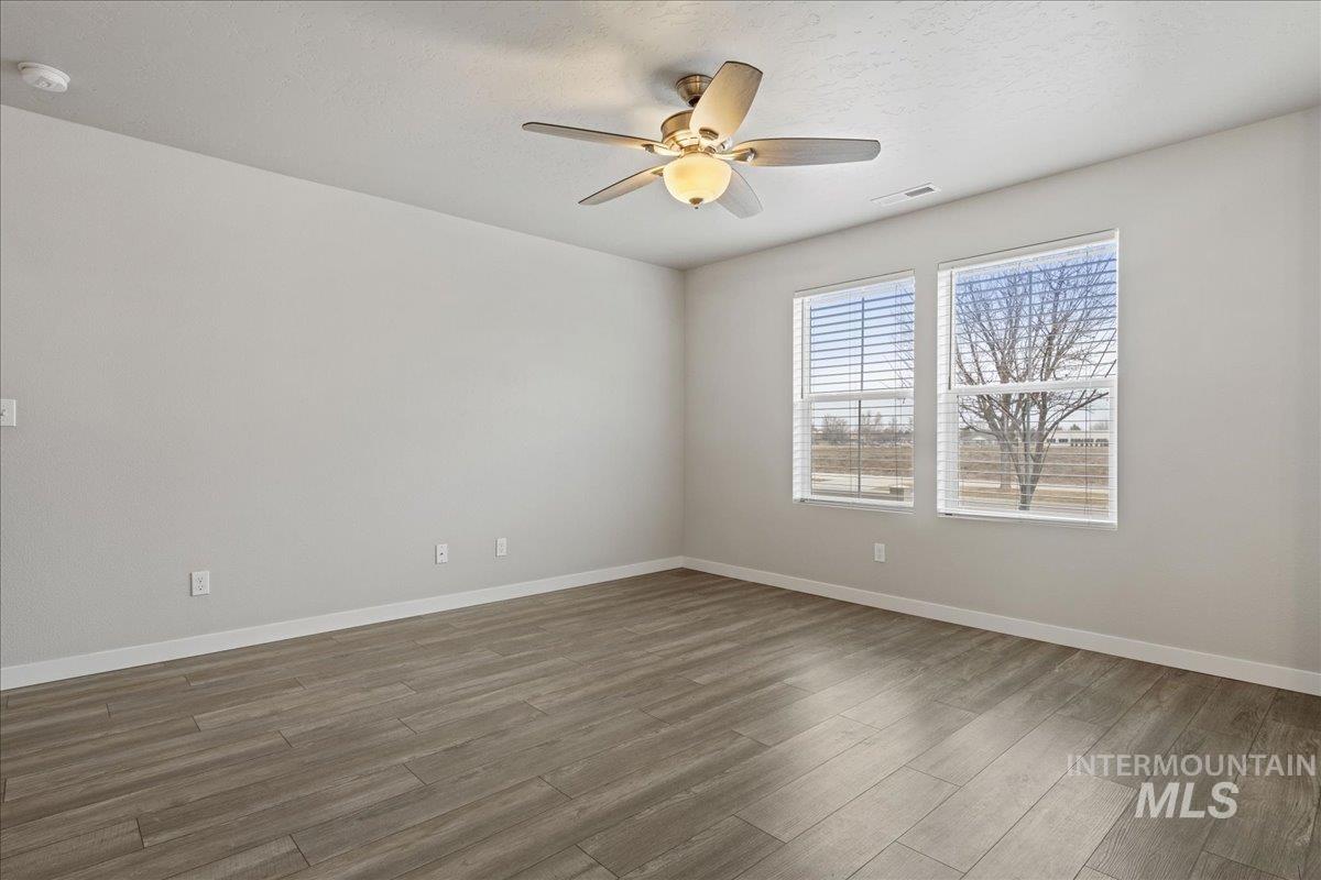 2479 East Goldstone Street Meridian, ID 83642 - Photo 5 of 29 Empty room featuring light wood-style floors, ceiling fan, and a textured ceiling