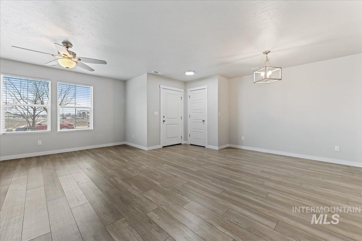 2479 East Goldstone Street Meridian, ID 83642 - Photo 8 of 29 Unfurnished living room with light wood-type flooring, a ceiling fan, and hanging lights