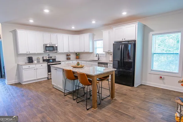 a large kitchen with kitchen island a large counter top space a sink stainless steel appliances and cabinets