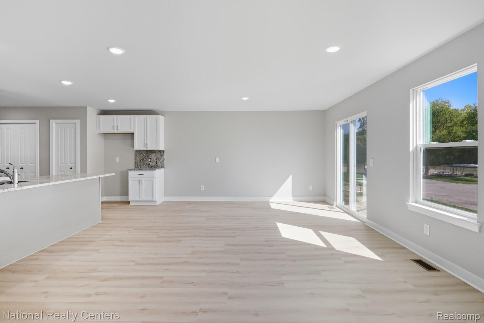 25018 Reeck Road Trenton, MI 48183 - Photo 13 of 32 Recessed lighting, wood-finish flooring, white cabinetry, granite-finish backsplash, and a sliding glass door