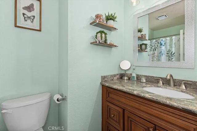 a bathroom with a granite countertop sink a toilet and a mirror