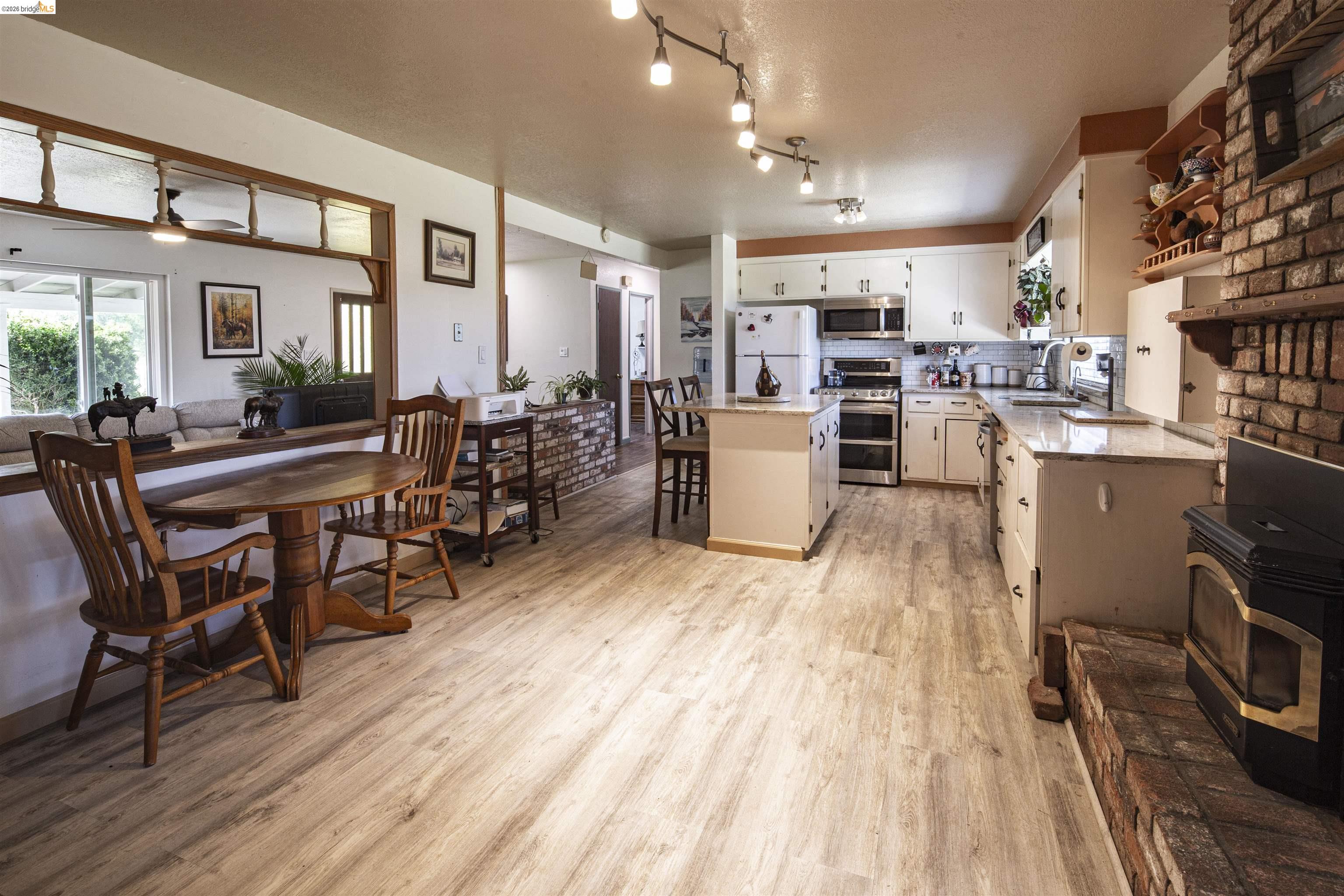 10458 Southworth Road Valley Springs, CA 95252 - Photo 11 of 22 Kitchen featuring a center island, stainless steel appliances, a wood stove, light wood finished floors, and light stone counters