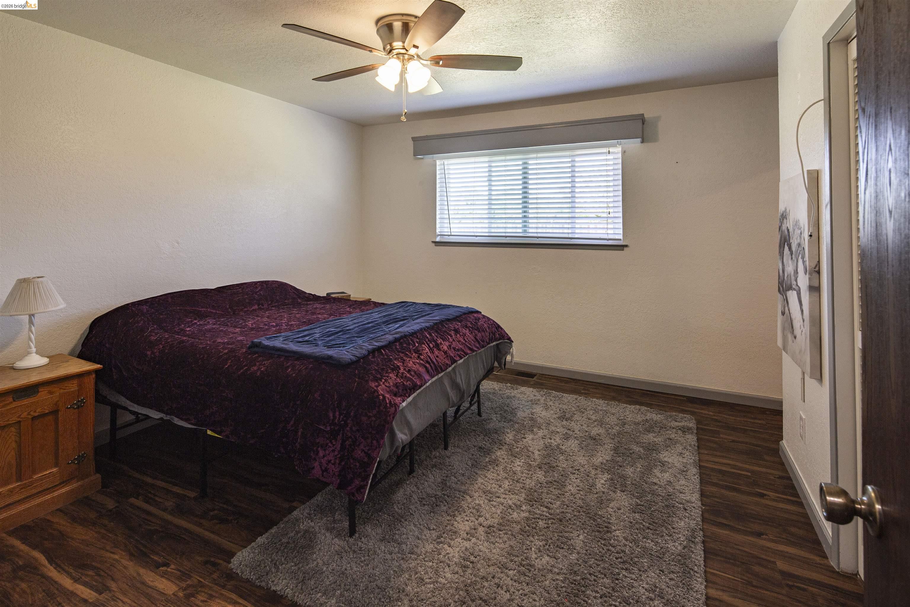 10458 Southworth Road Valley Springs, CA 95252 - Photo 13 of 22 Bedroom featuring dark wood-style flooring, ceiling fan, and a textured ceiling
