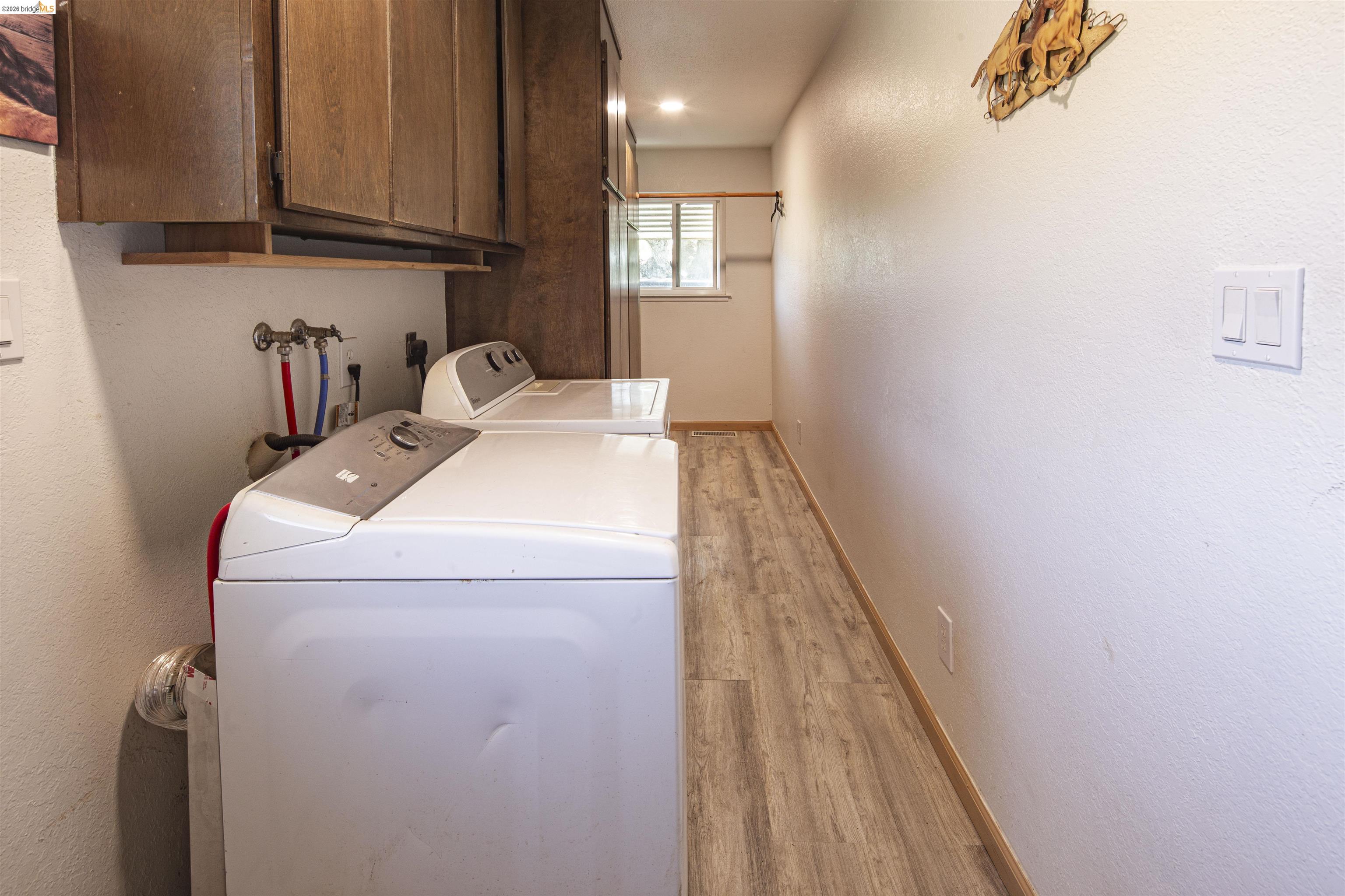 10458 Southworth Road Valley Springs, CA 95252 - Photo 17 of 22 Laundry area with a textured wall, light wood-style flooring, cabinet space, washing machine and clothes dryer, and recessed lighting