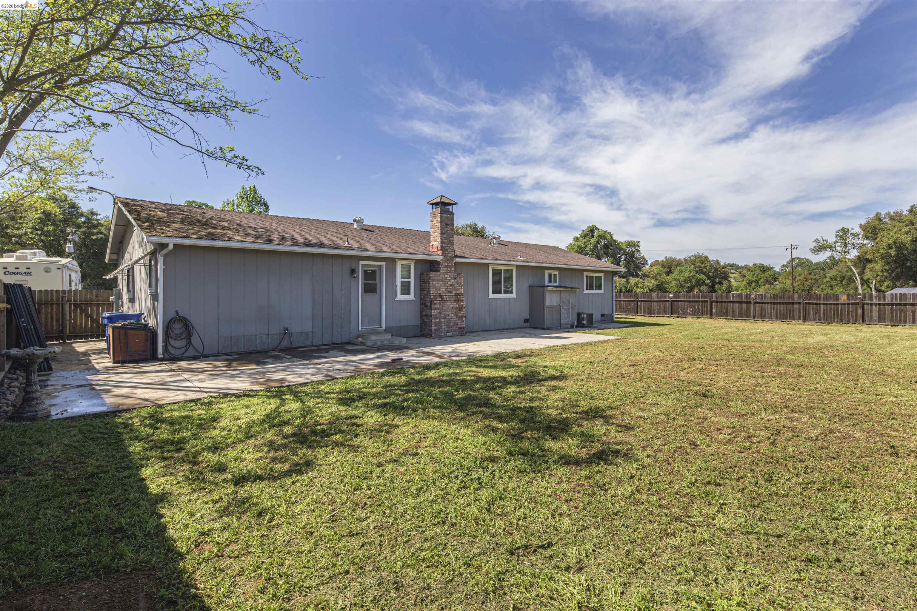 10458 Southworth Road Valley Springs, CA 95252 - Photo 21 of 22 Back of property with a fenced backyard, a chimney, and a patio