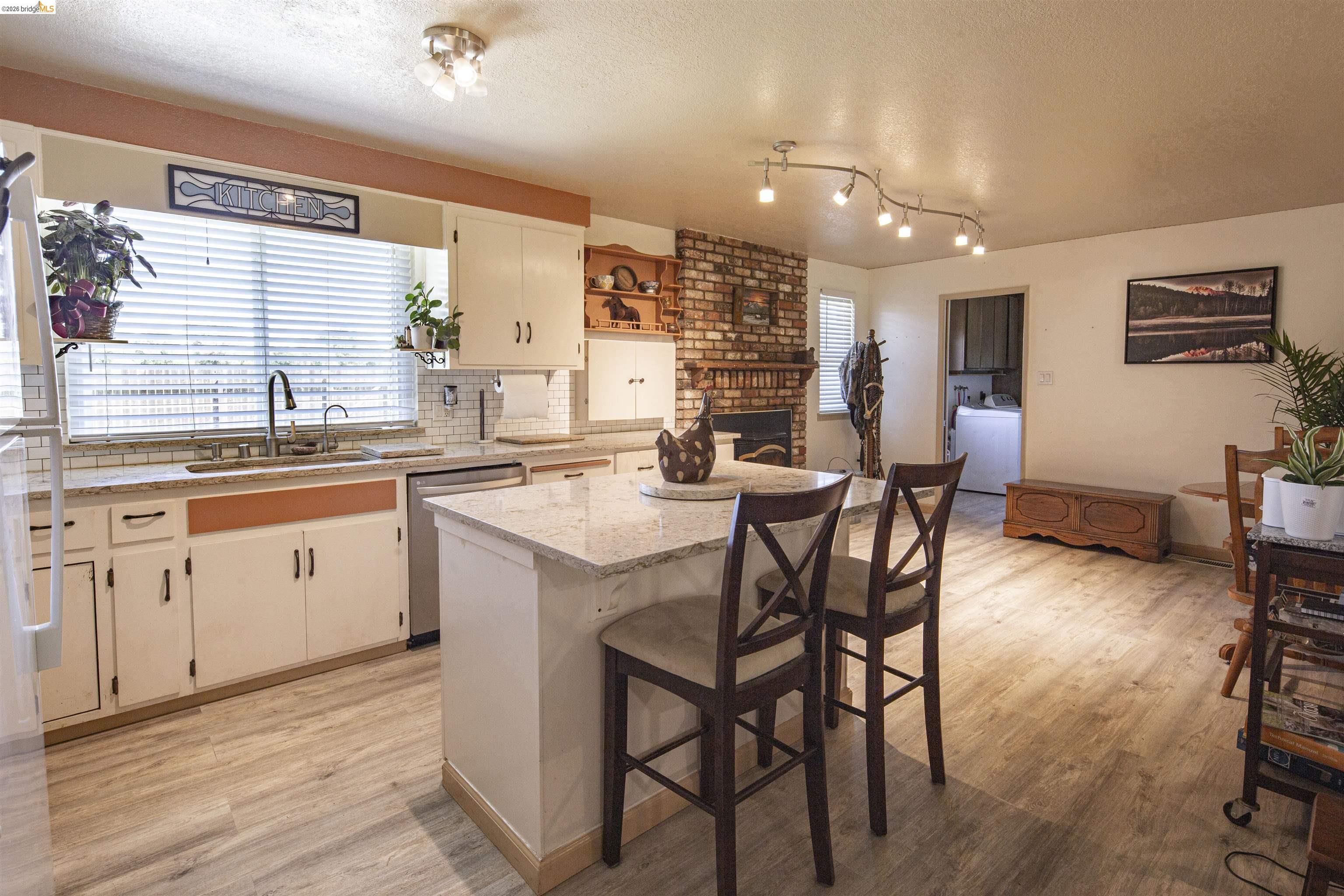 10458 Southworth Road Valley Springs, CA 95252 - Photo 9 of 22 Kitchen with a textured ceiling, a breakfast bar area, light stone counters, backsplash, and a center island