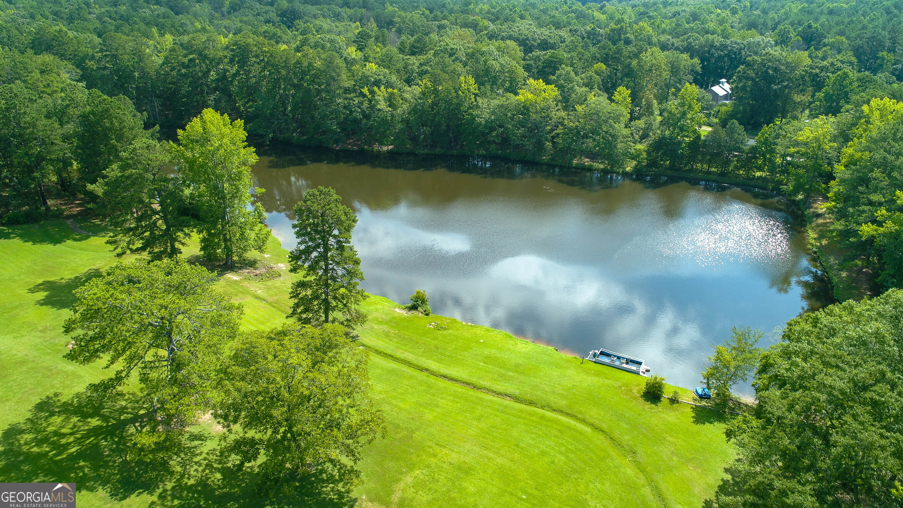 an aerial view of a residential houses with outdoor space and trees all around