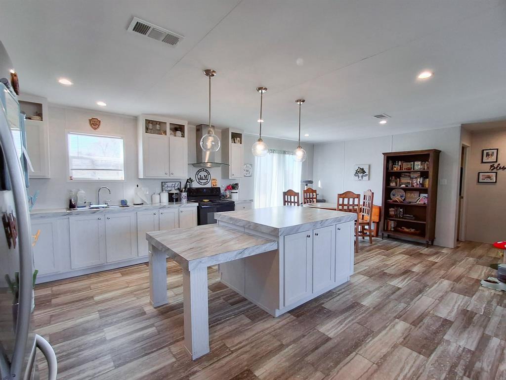 7256 Johnson Road Granbury, TX 76049 - Photo 16 of 40 Kitchen featuring white cabinets, light countertops, pendant lighting, wall chimney range hood, and recessed lighting