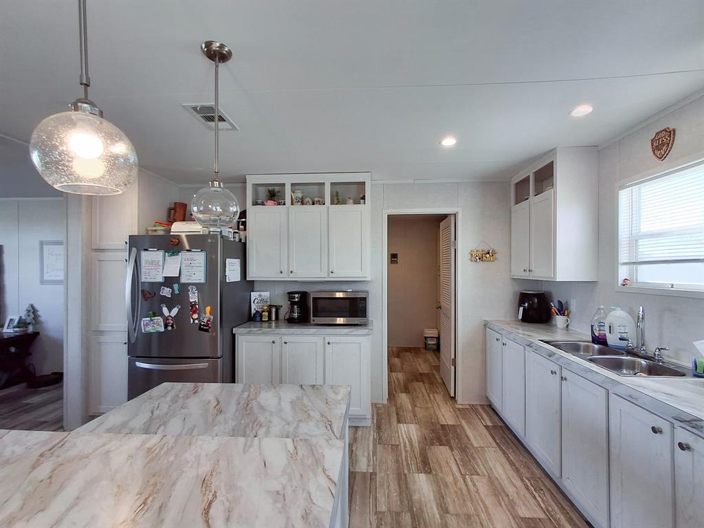 7256 Johnson Road Granbury, TX 76049 - Photo 19 of 40 Kitchen with white cabinets, stainless steel appliances, decorative light fixtures, light wood-style flooring, and glass insert cabinets