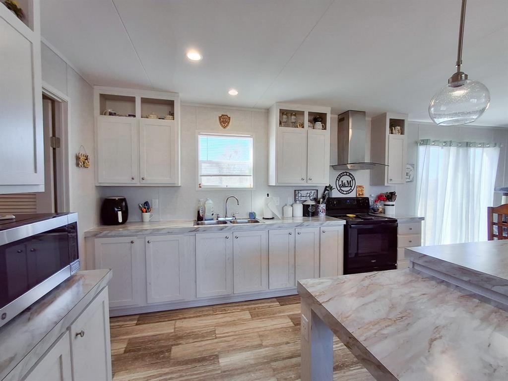 7256 Johnson Road Granbury, TX 76049 - Photo 20 of 40 Kitchen with black electric range, stainless steel microwave, wall chimney exhaust hood, white cabinets, and recessed lighting