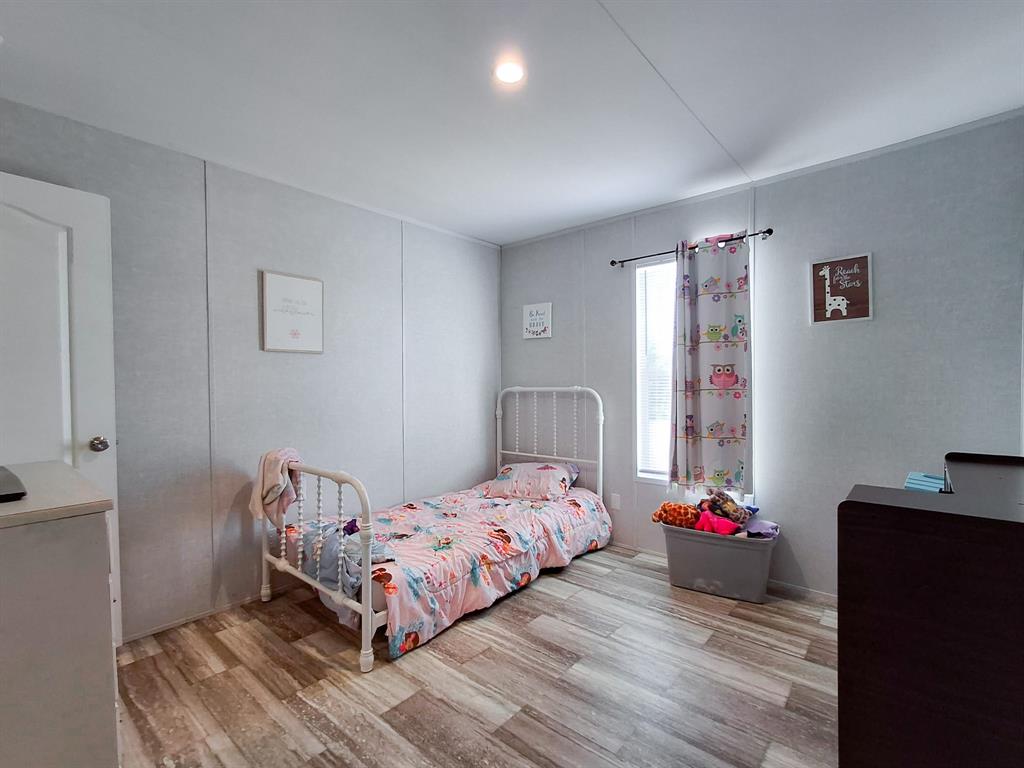 7256 Johnson Road Granbury, TX 76049 - Photo 36 of 40 Bedroom featuring light wood-type flooring and a decorative wall