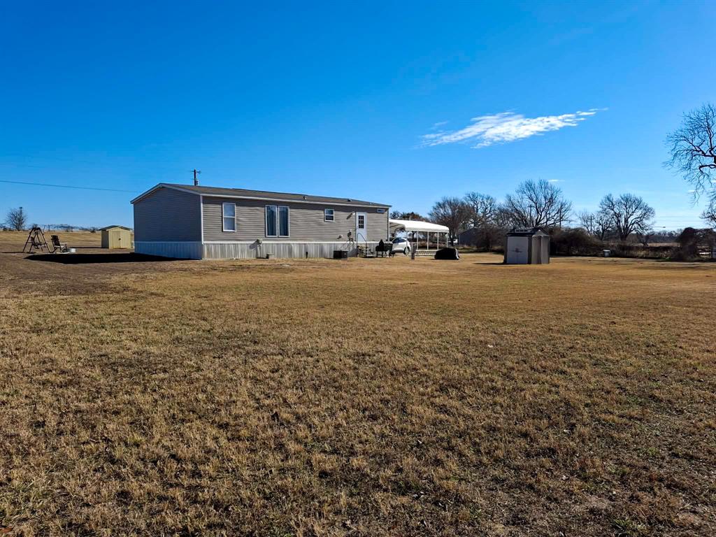 7256 Johnson Road Granbury, TX 76049 - Photo 38 of 40 Rear view of house with a storage unit and a yard