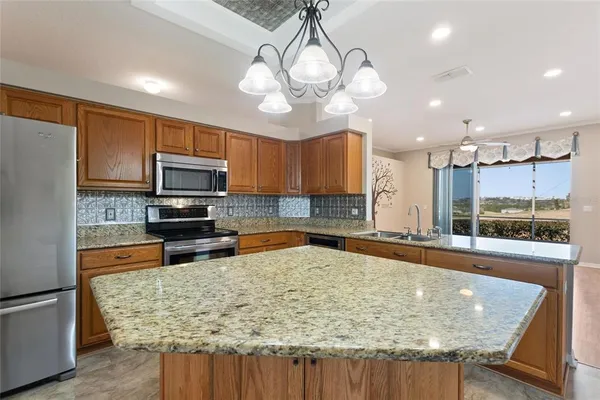 an empty room with wooden floor chandelier fan and windows