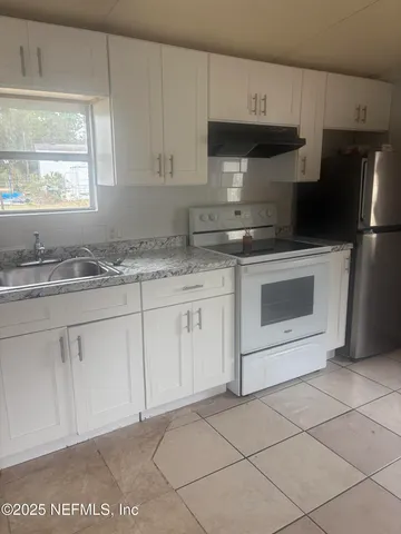 a kitchen with granite countertop white cabinets stainless steel appliances a sink and a window