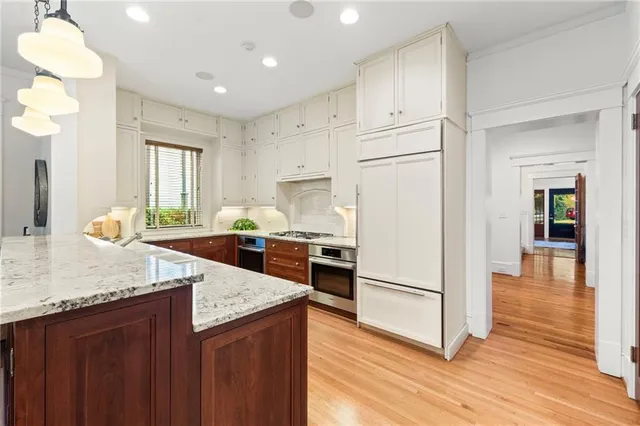 a kitchen with granite countertop a refrigerator a sink dishwasher and wooden cabinets with wooden floor