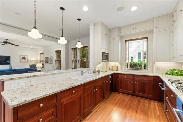 a large kitchen with kitchen island granite countertop wooden floors and white cabinets
