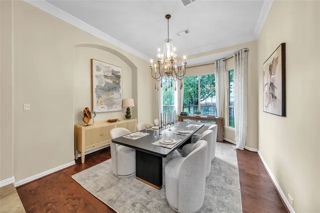 a dining room with wooden floor a chandelier a wooden table and chairs