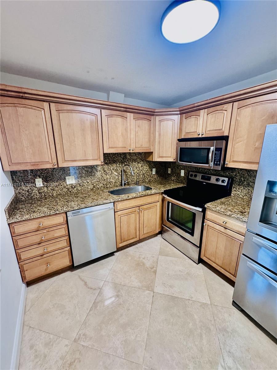 a kitchen with stainless steel appliances granite countertop a stove a sink and a microwave