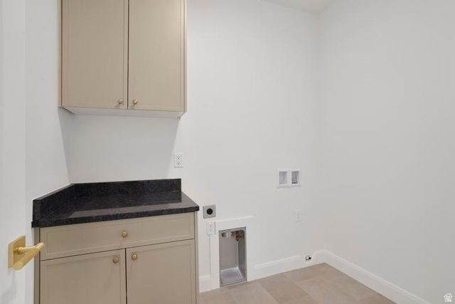 990 Manen Street Washington, UT 84780 - Photo 28 of 43 Laundry room featuring light-colored cabinetry with gold-toned hardware, a dark countertop, and tiled flooring