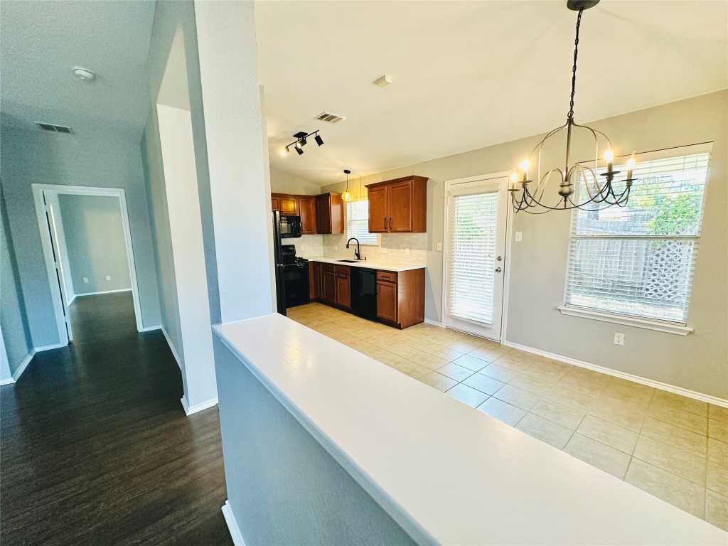 12112 Rancho Alto Road Austin, TX 78748 - Photo 16 of 34 a large kitchen with kitchen island a stove a wooden floor and chandelier