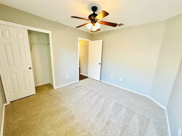 a view of an empty room with a chandelier fan