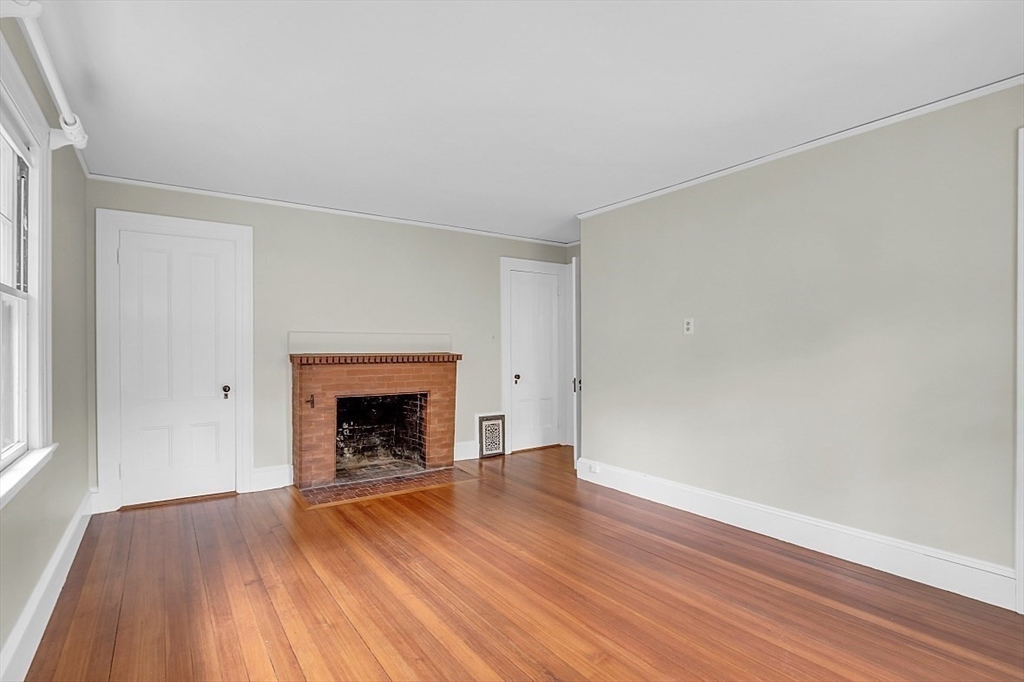 24 Sandy Pond Road Lincoln, MA 01773 - Photo 30 of 42 an empty room with wooden floor fireplace and windows