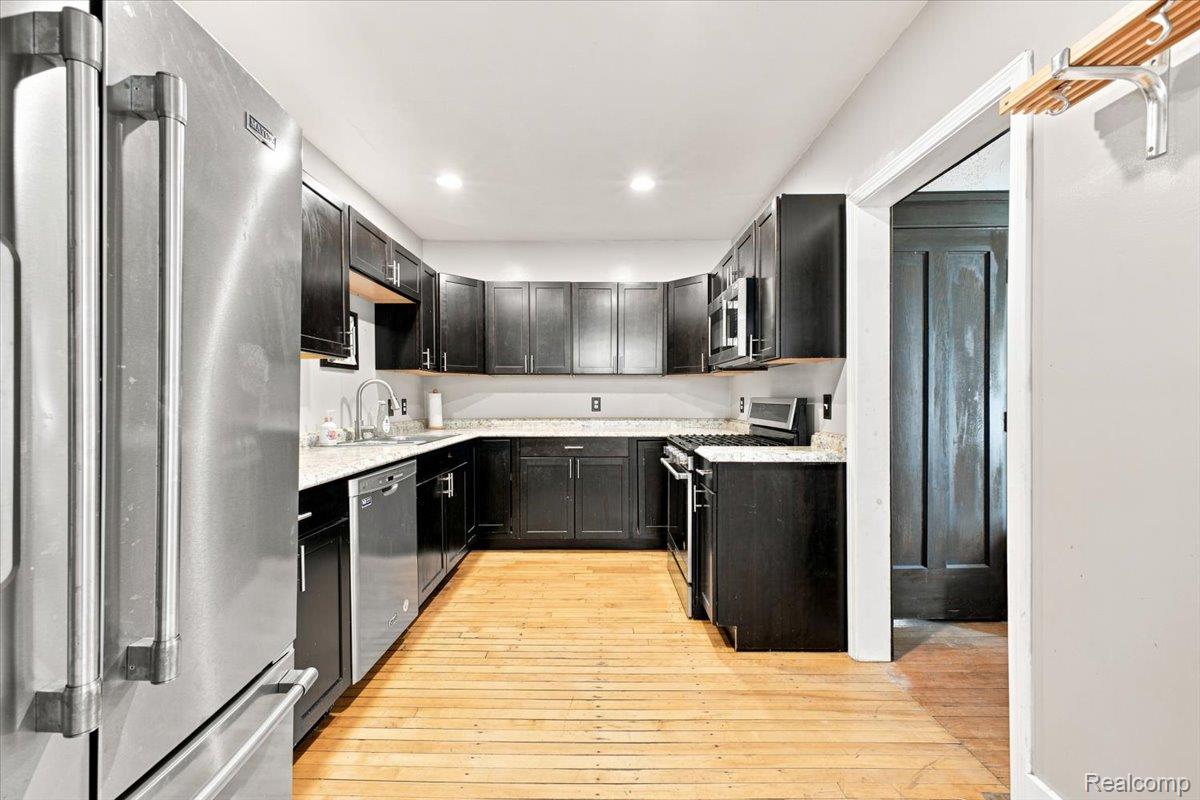 899 Edison Street Detroit, MI 48202 - Photo 10 of 37 Kitchen featuring U-shaped dark cabinetry, light-toned countertops, stainless steel appliances, and wood-finish flooring