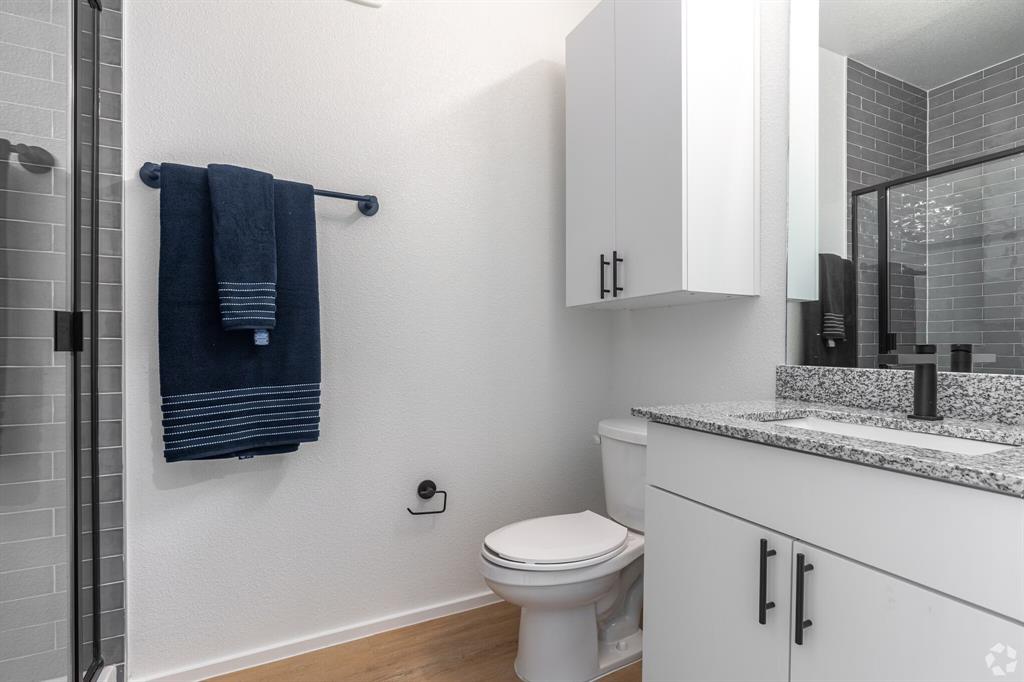 596 West 9th Street, Unit 339 Dallas, TX 75208 - Photo 13 of 22 Bathroom featuring vanity, a shower stall, light wood-style floors, and a textured wall