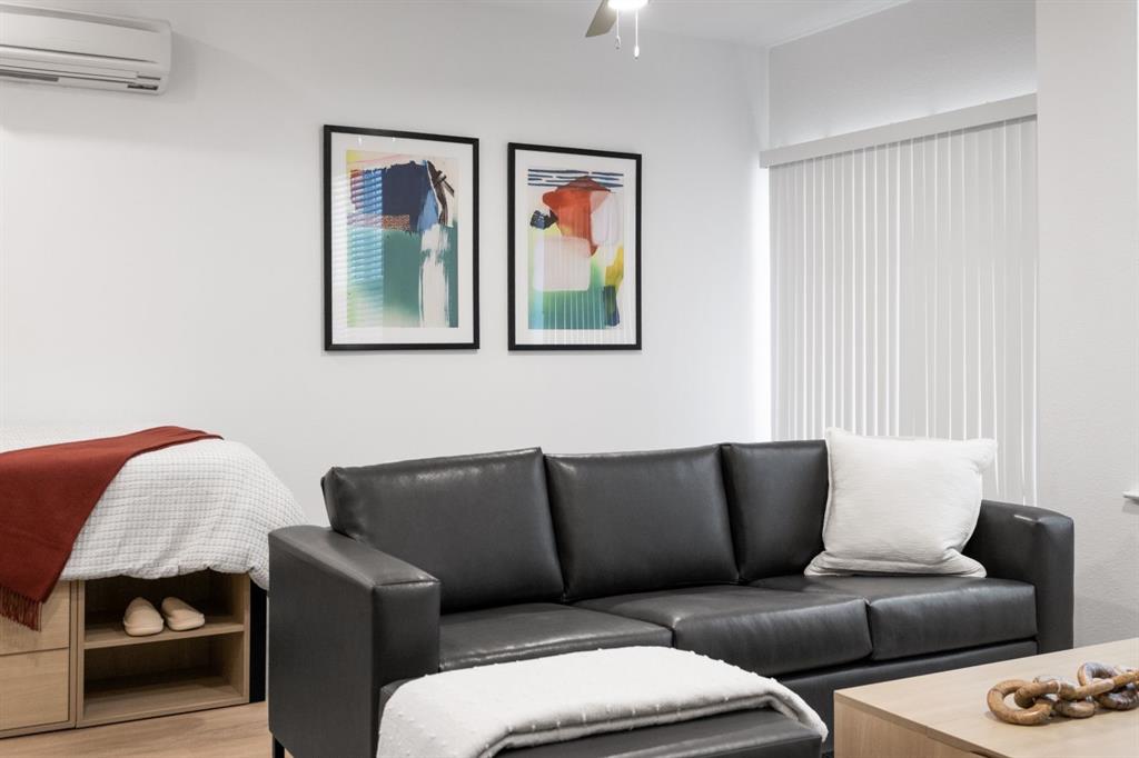 596 West 9th Street, Unit 339 Dallas, TX 75208 - Photo 18 of 22 Living area with a wall mounted air conditioner, a ceiling fan, and wood finished floors
