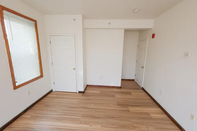 a view of an empty room with wooden floor and closet