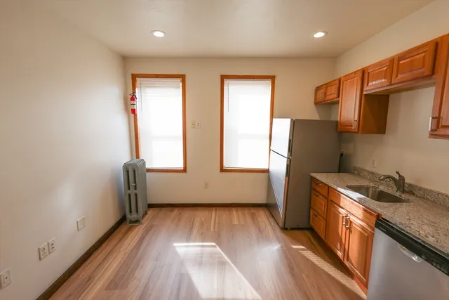 a kitchen with granite countertop a refrigerator a sink a stove and wooden floor