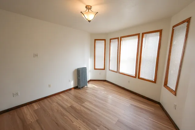 a view of an empty room with a window and wooden floor