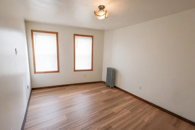 an empty room with wooden floor cabinet and windows