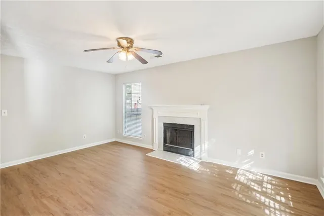 an empty room with windows fireplace and fan
