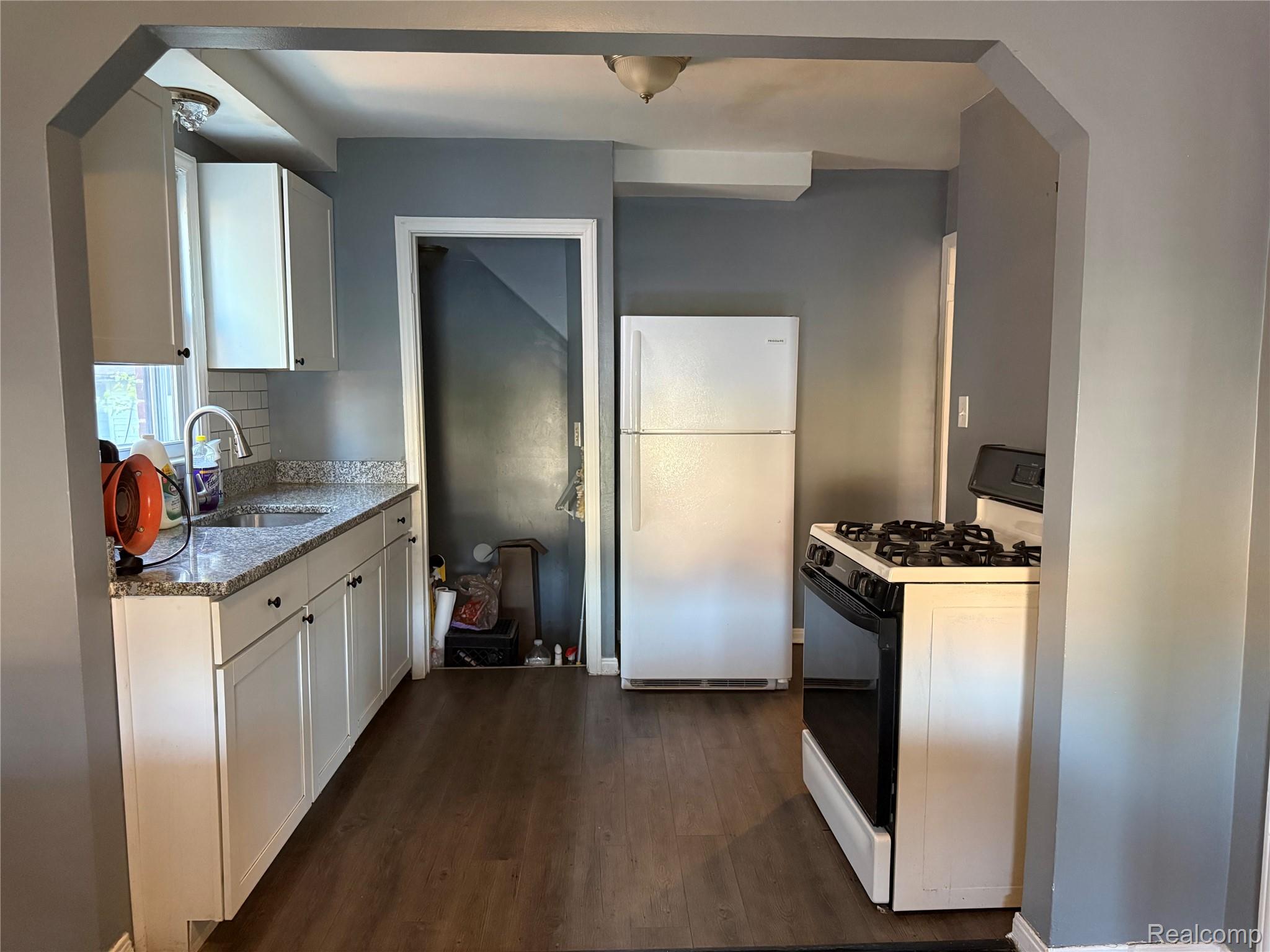 7633 Fielding Street Detroit, MI 48228 - Photo 5 of 12 Kitchen featuring granite-style countertops, subway tile backsplash, white cabinetry with dark hardware, and wood-finish flooring