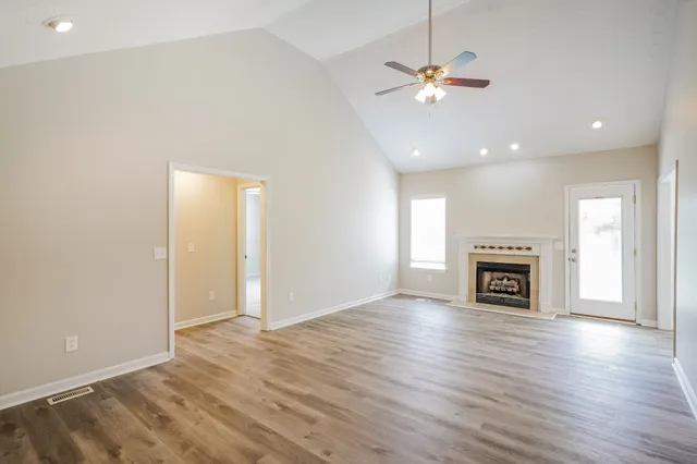 an empty room with fireplace fan and windows