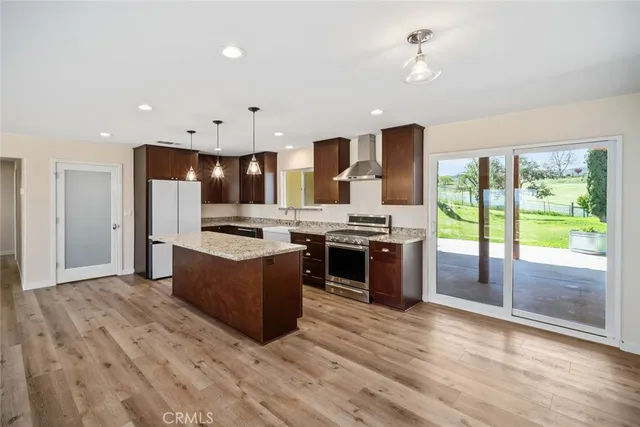 a large kitchen with stainless steel appliances kitchen island granite countertop a large stove a sink a refrigerator and island with wooden floor