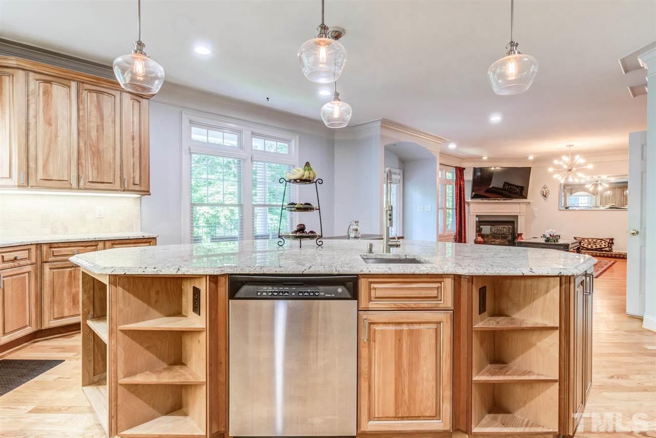 12249 Beestone Lane Raleigh, NC 27614 - Photo 9 of 29 a open kitchen with granite countertop a stove a sink a dining table and chairs with wooden floor