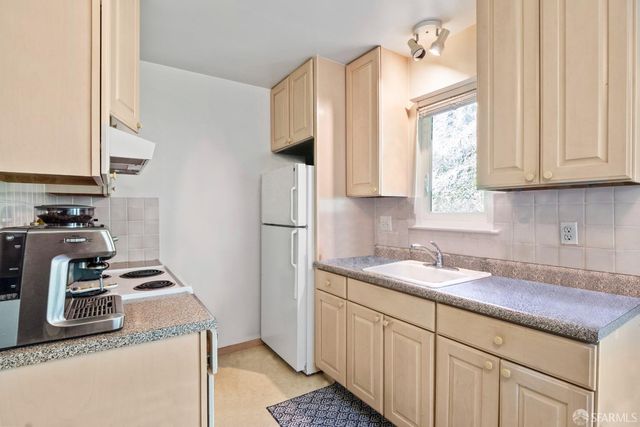 a kitchen with kitchen island granite countertop a sink stove and refrigerator