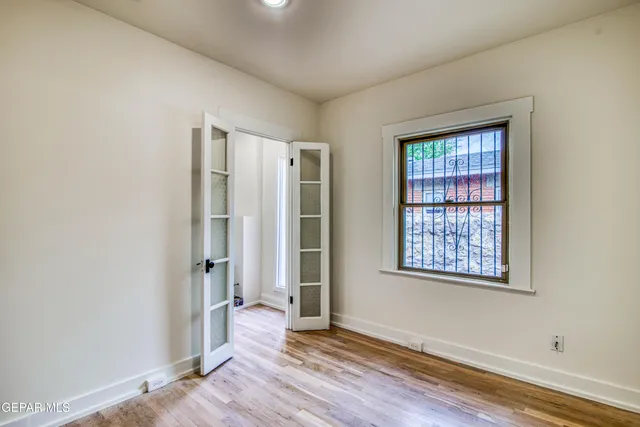 a view of an empty room with window fireplace and wooden floor