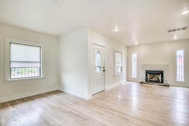a view of a big room with wooden floor and windows