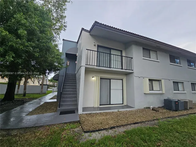 a view of a house with a small yard and large tree