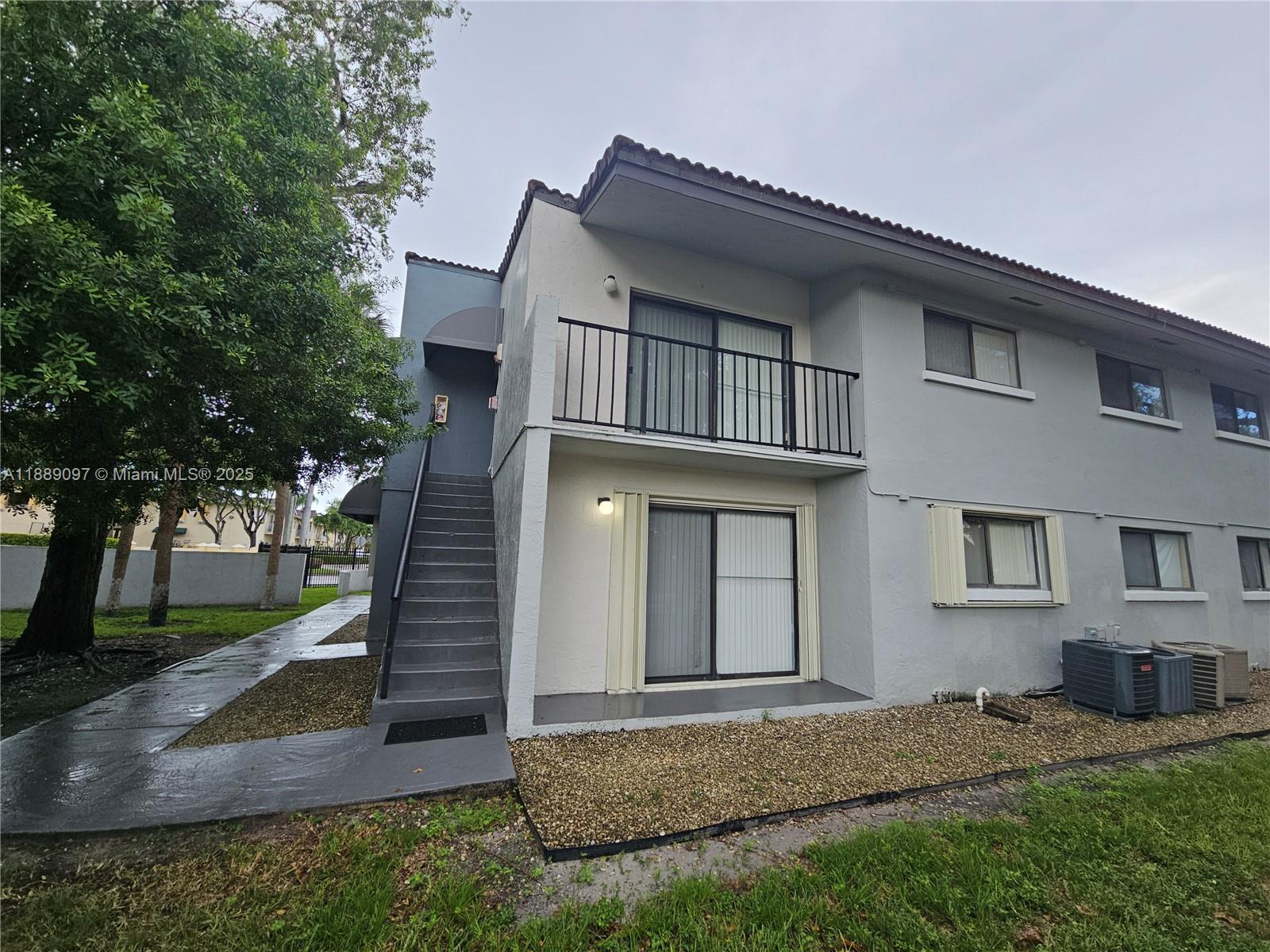 6901 Northwest 179th Street, Unit 212 Hialeah, FL 33015 - Photo 2 of 5 a view of a house with a small yard and large tree