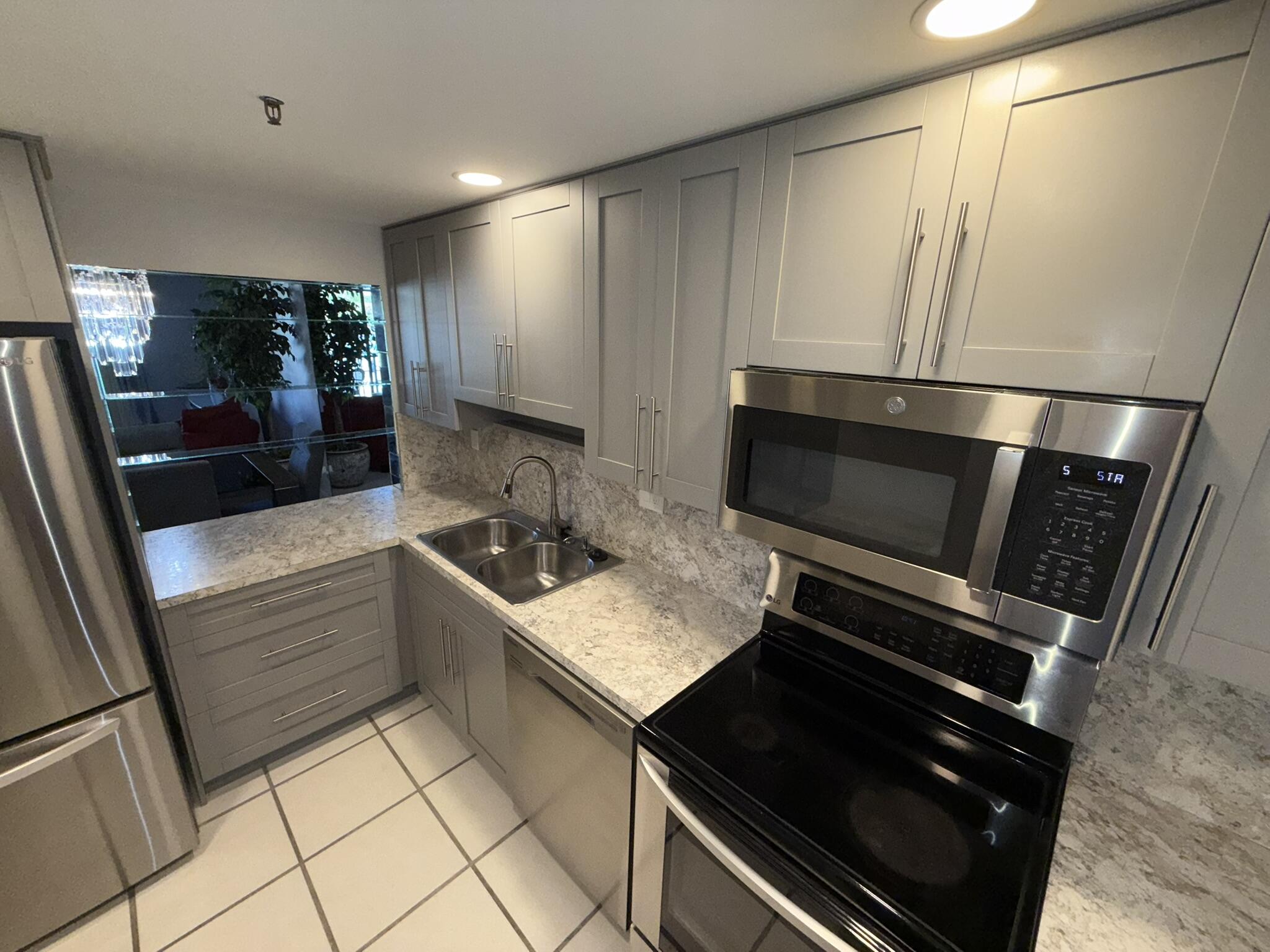 2788 Tennis Club Drive, Unit 203 West Palm Beach, FL 33417 - Photo 3 of 10 a kitchen with kitchen island granite countertop cabinets and steel stainless steel appliances