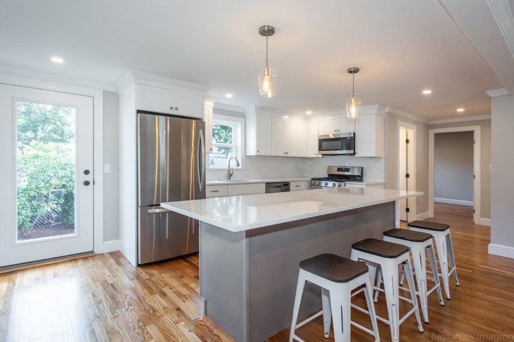 214 Riverside Drive Dedham, MA 02026 - Photo 4 of 26 a kitchen with kitchen island granite countertop wooden floors and white cabinets