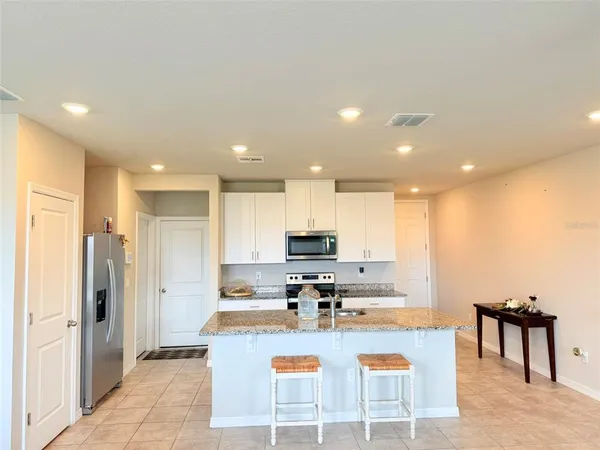 a kitchen with kitchen island granite countertop a sink and a refrigerator